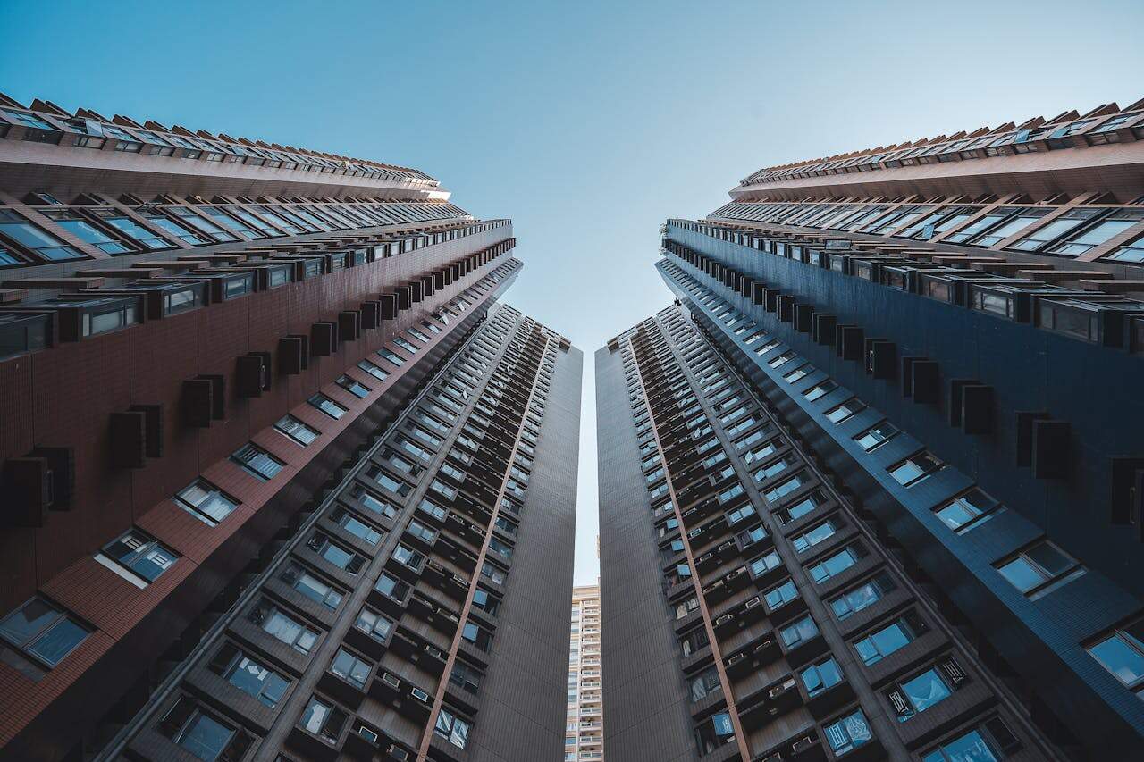 Looking up at symmetrical high-rise buildings against a blue sky in Hong Kong.