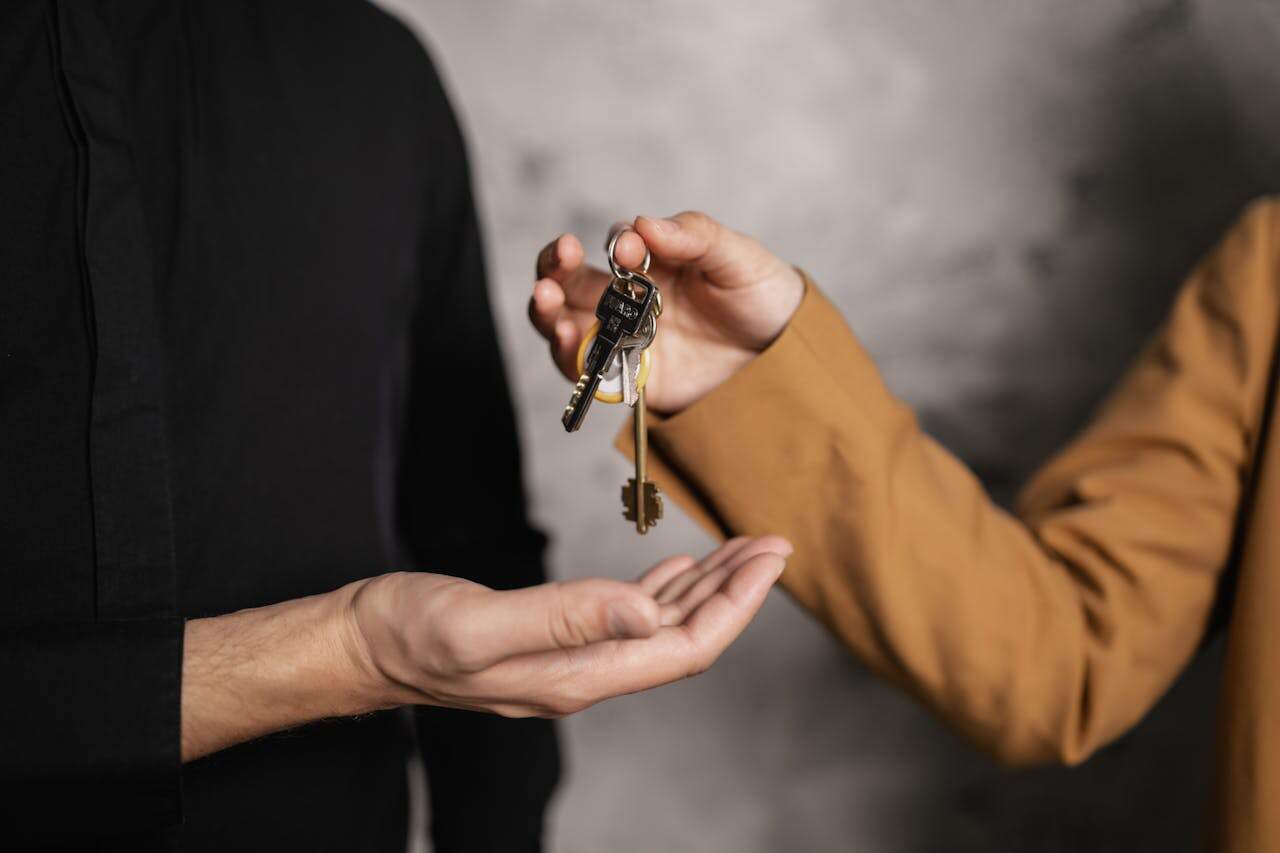 about-us-01 Detailed close-up of one person handing over keys to another, symbolizing a real estate transaction.